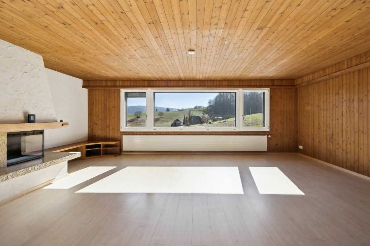 Leerer Wohnraum mit Kamin und Panoramafenster