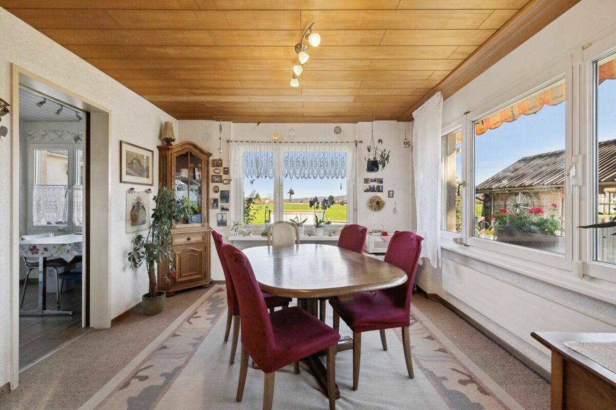 Esszimmer mit großem Fenster und Holzbalkendecke