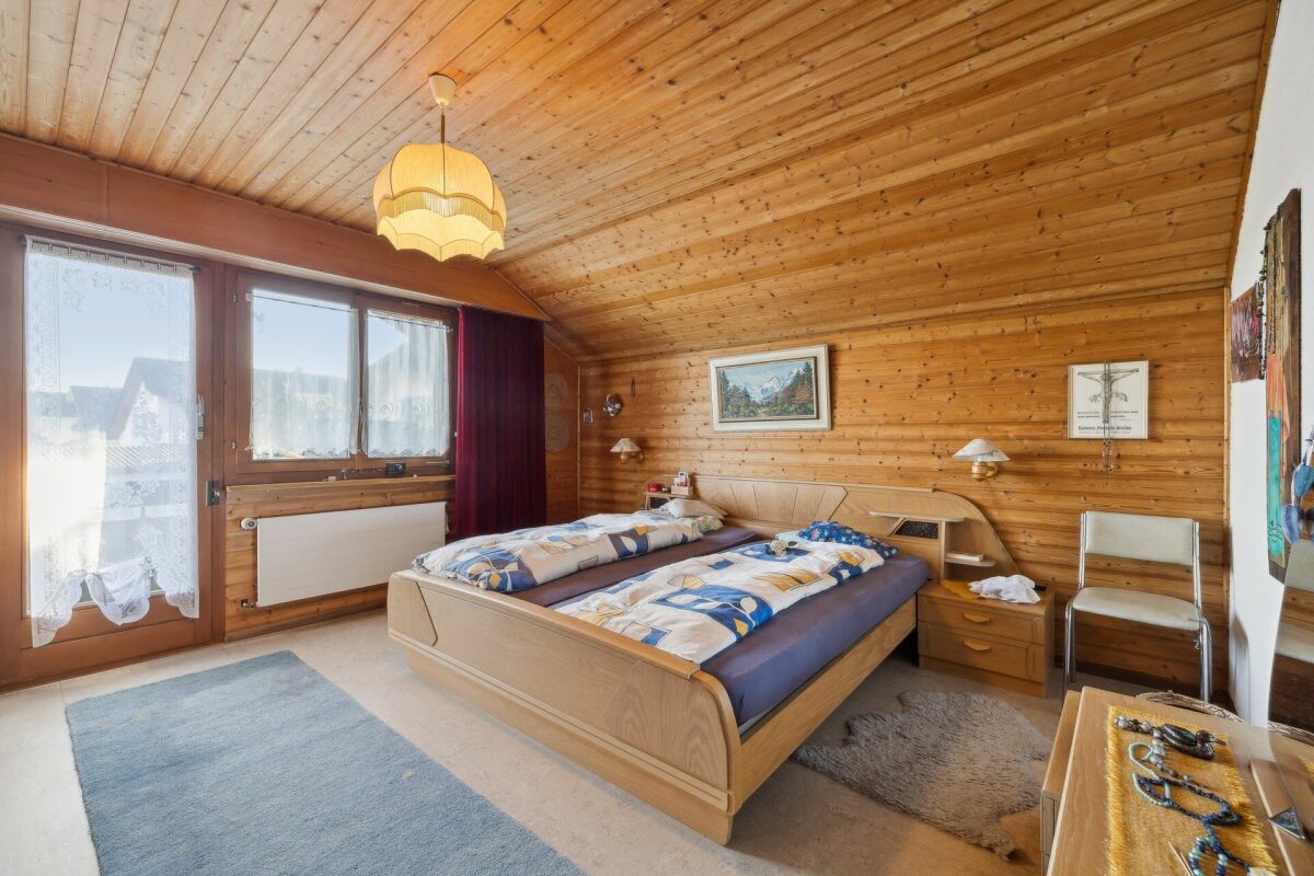 Gemütliches Schlafzimmer mit Holzvertäfelung und Balkonzugang