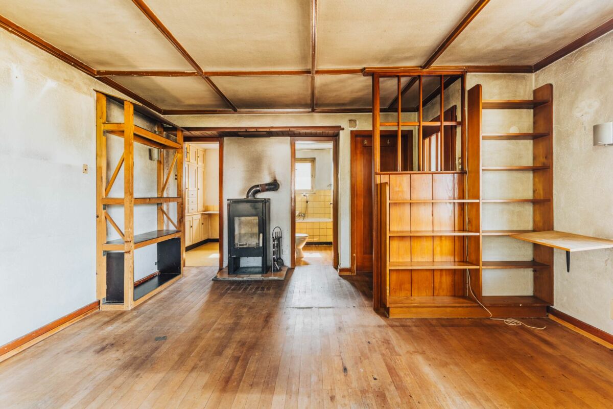 Leerer Wohnraum mit Holzregalen und Kaminofen