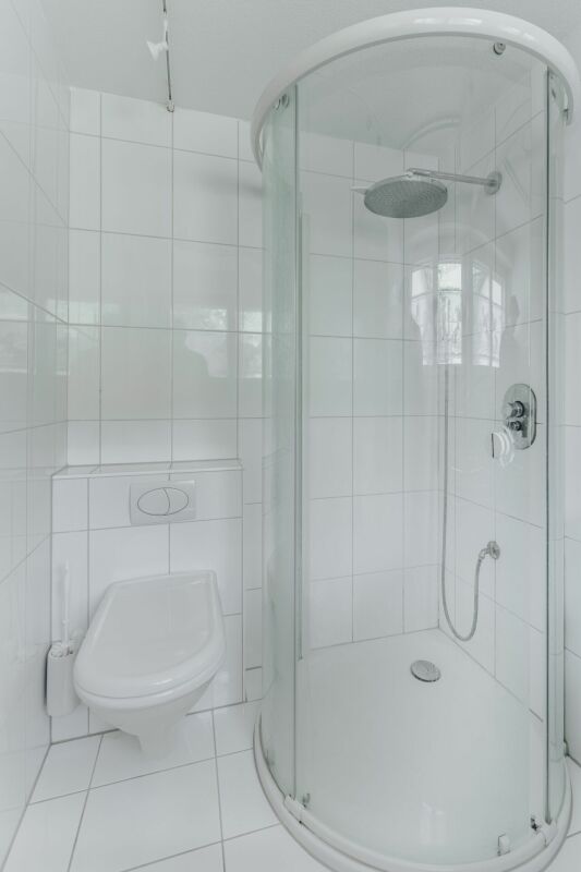 Kleines weißes Badezimmer mit Dusche und WC