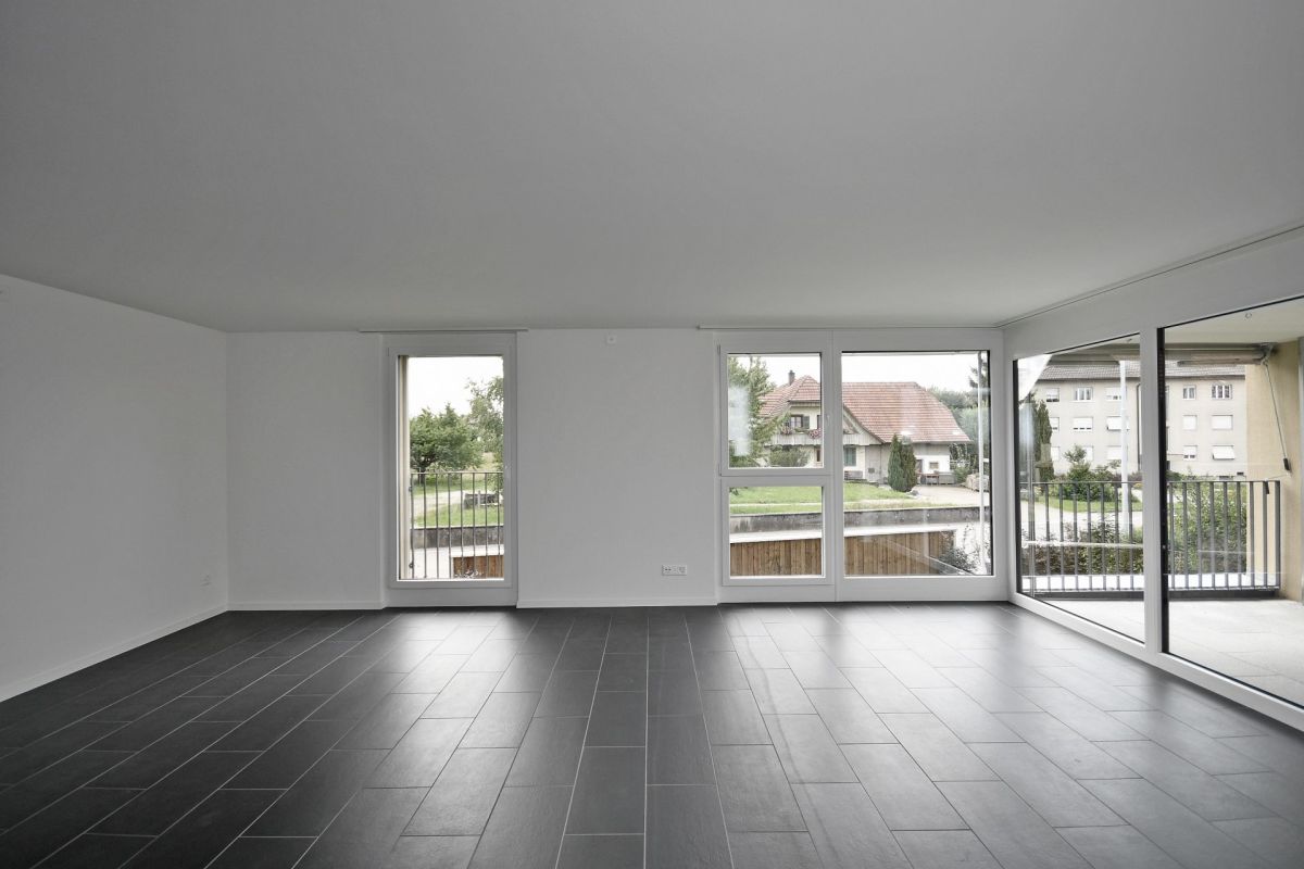 Leerer, moderner Wohnraum mit großen Fensterflächen und Balkon