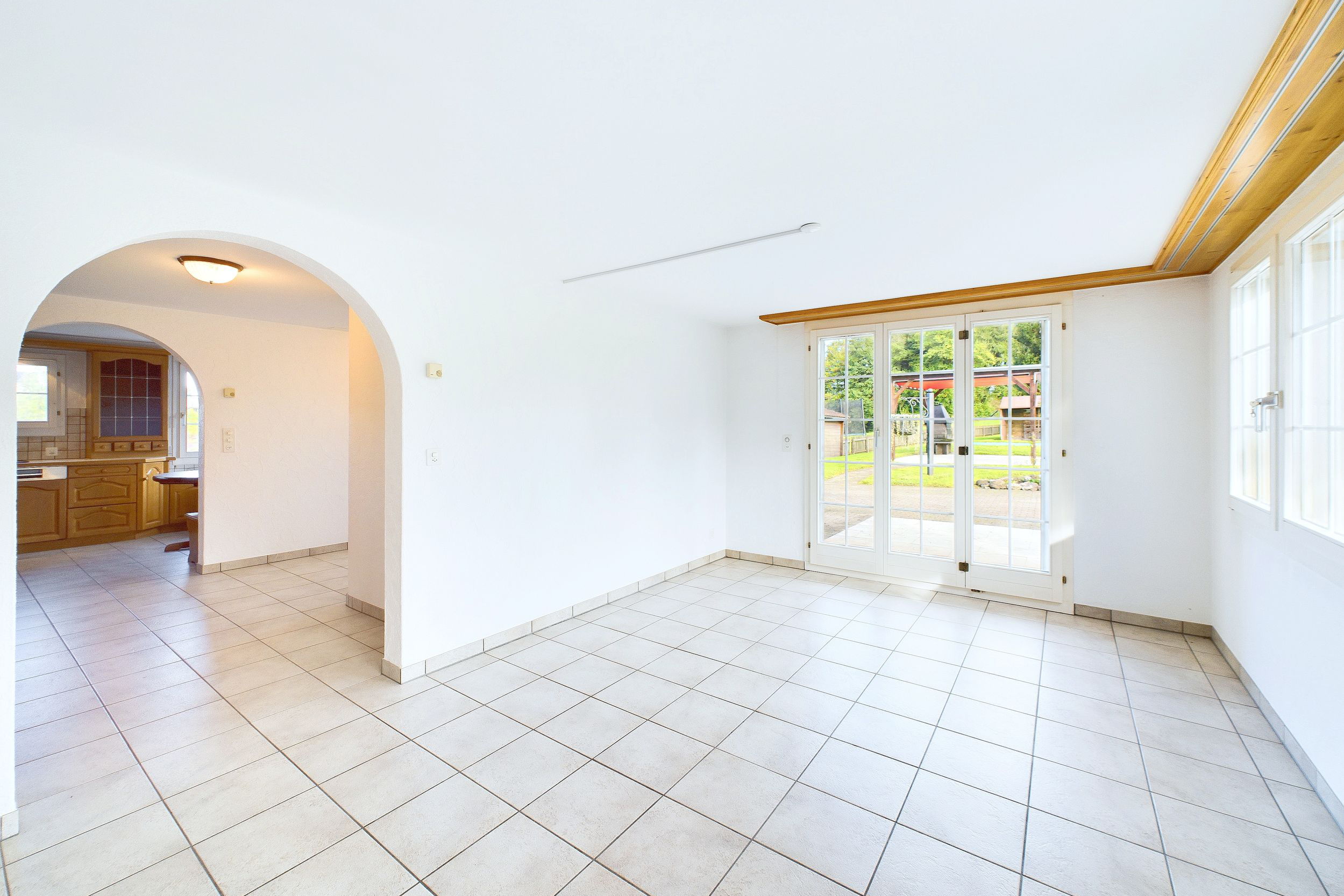 Heller Wohnraum mit Fliesenboden und Blick in den Garten
