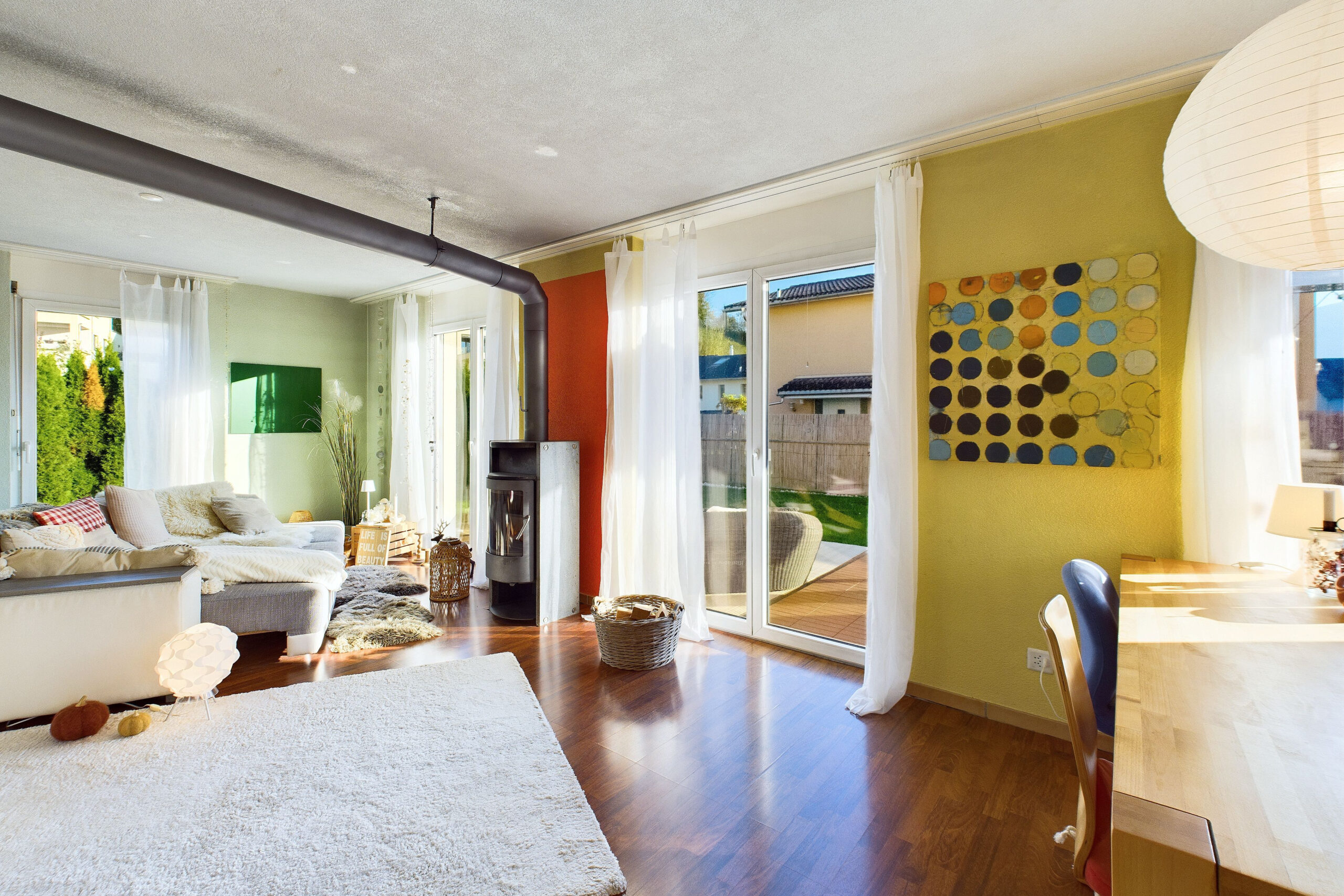 Helles Wohnzimmer mit Holzofen und Gartenblick