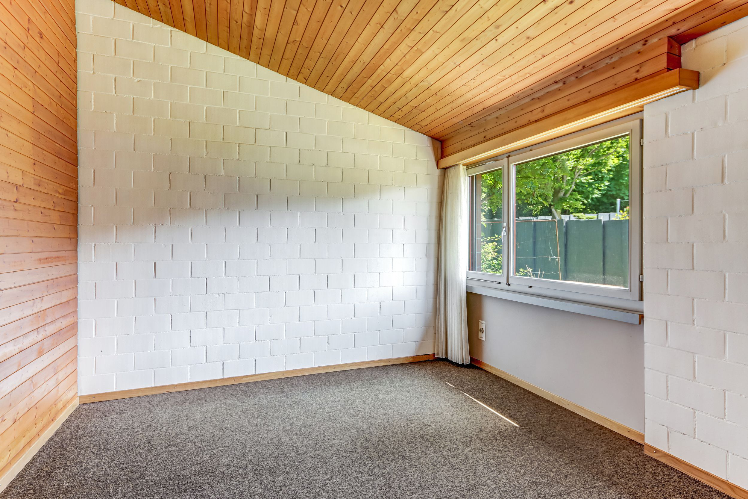 Leerer Raum mit Holzdecke und Teppichboden