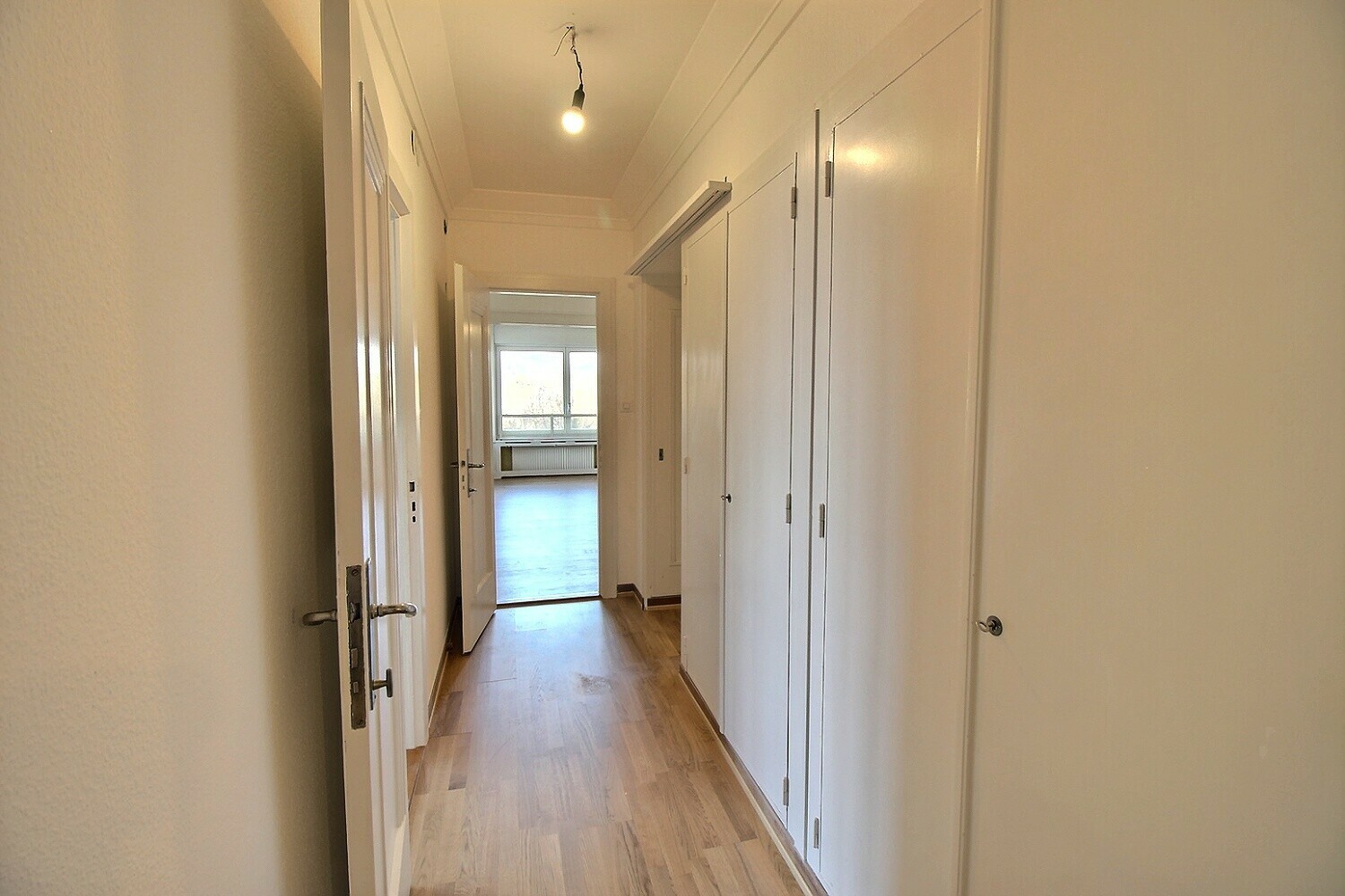 Heller Flur mit Holzboden und weißen Türen