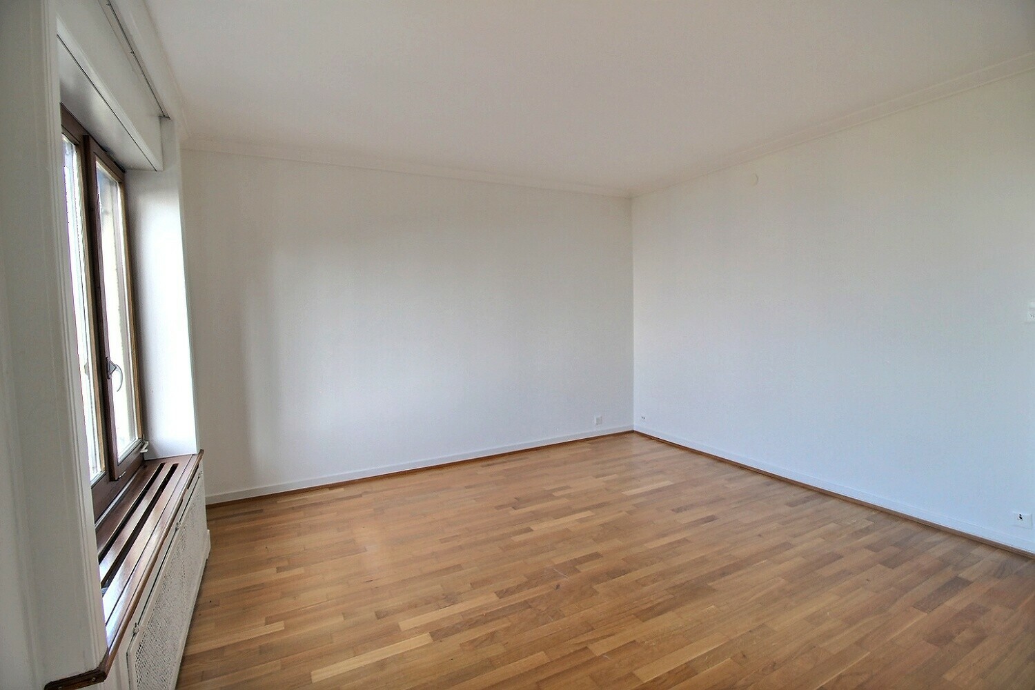 Heller leerer Raum mit Parkettboden und Fenster