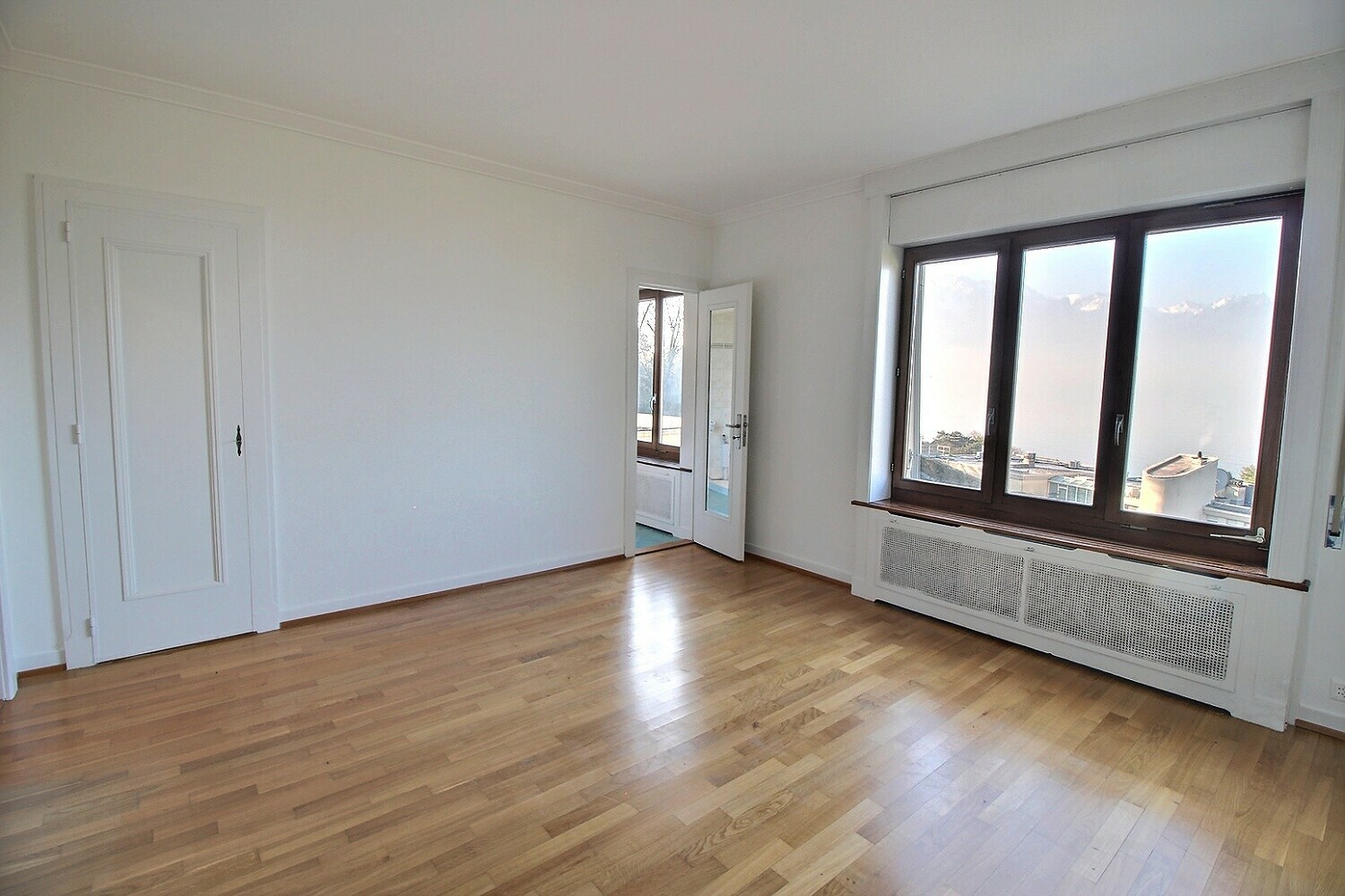 Heller leerer Raum mit Holzboden und zwei Fenstern