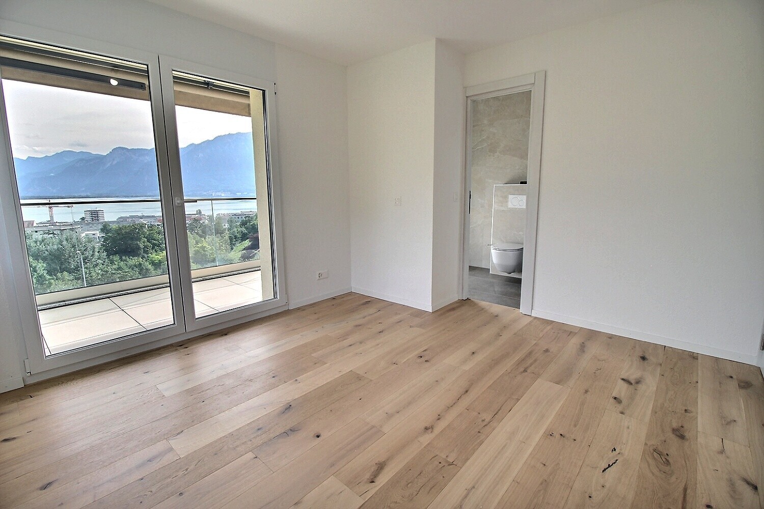 Heller leerer Raum mit Balkon und Bergblick