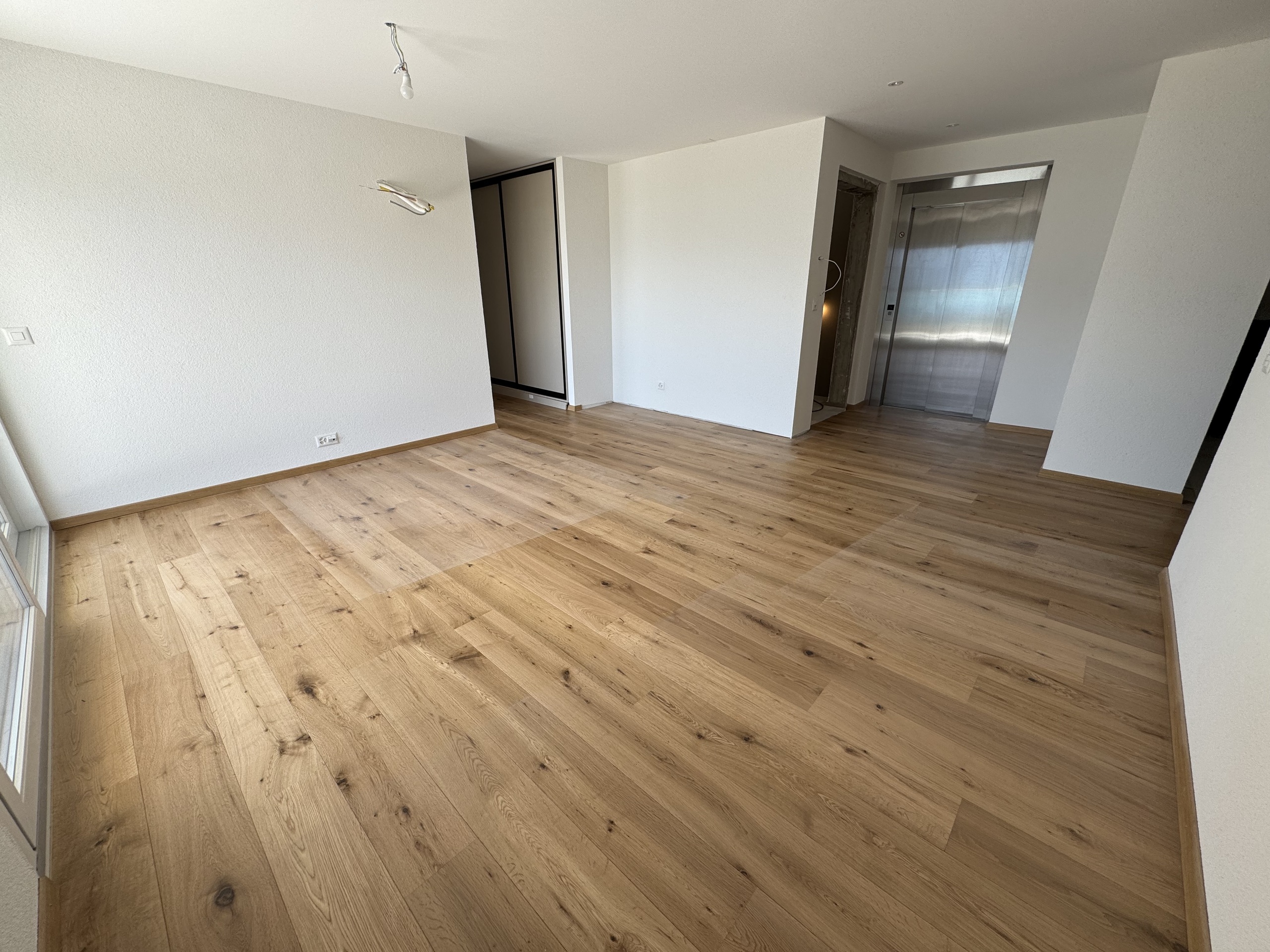 Leerer Wohnraum mit Aufzug und Holzboden