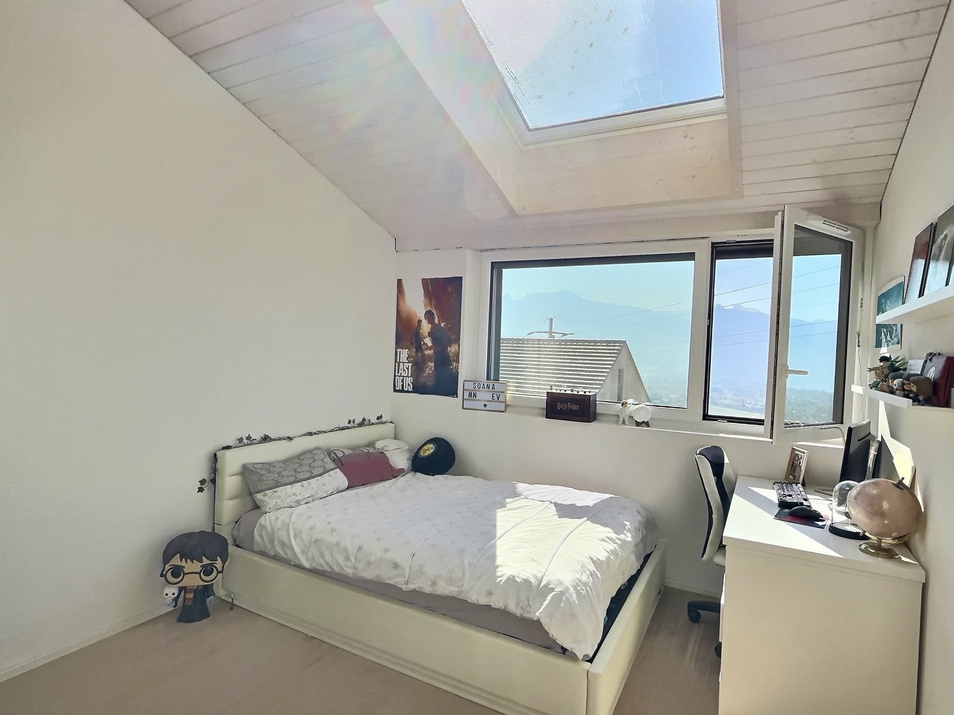 Helles Schlafzimmer mit Dachfenster und Bergblick