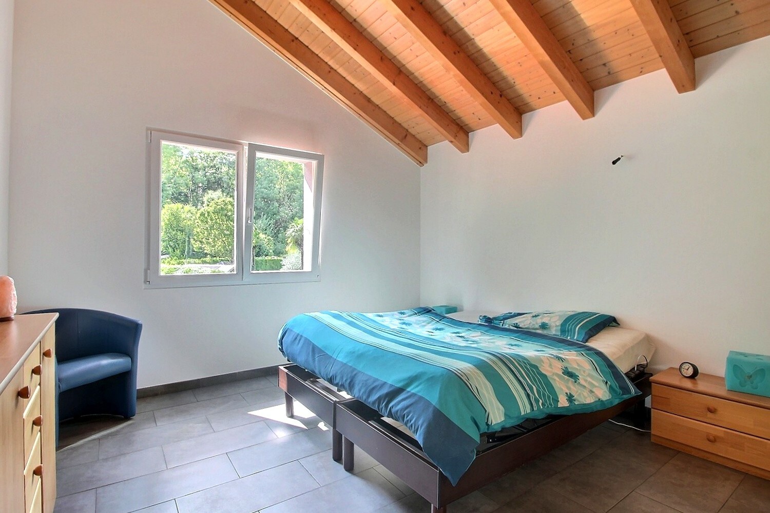 Helles Schlafzimmer mit Holzdecke und Gartenausblick