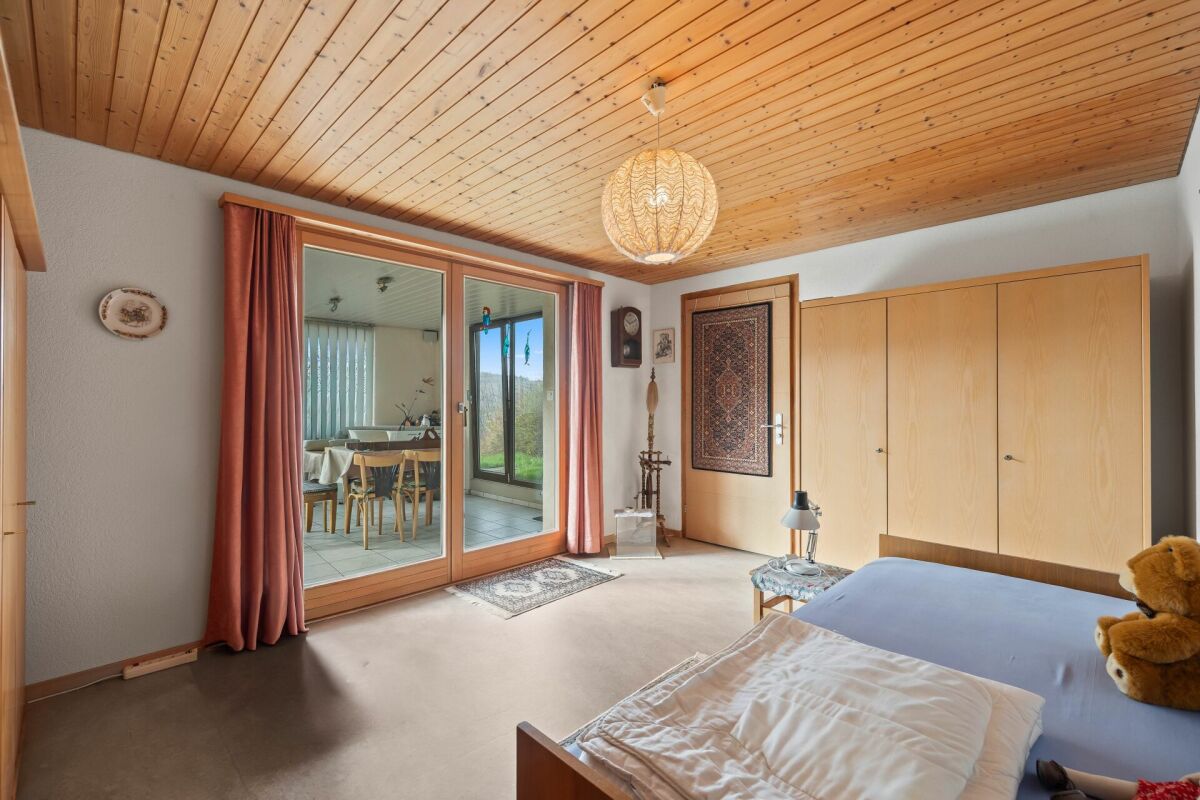 Schlafzimmer mit Holzdecke und Zugang zum Wintergarten