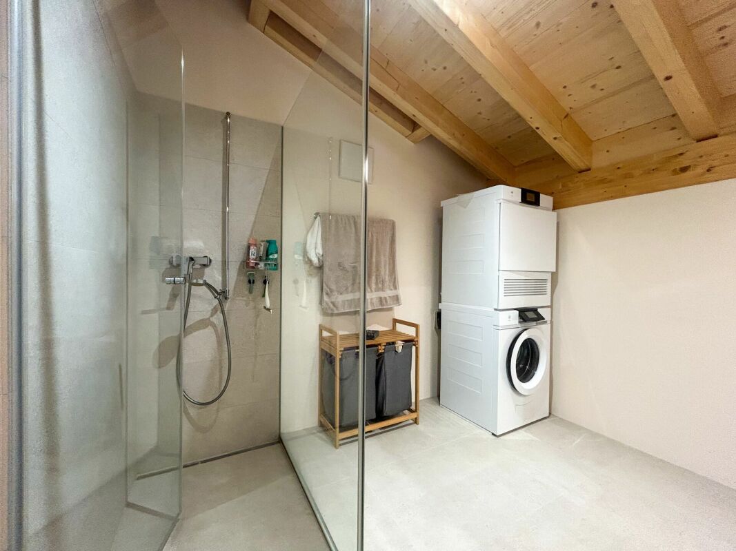 Badezimmer mit Waschmaschinenbereich und Holzbalkendecke