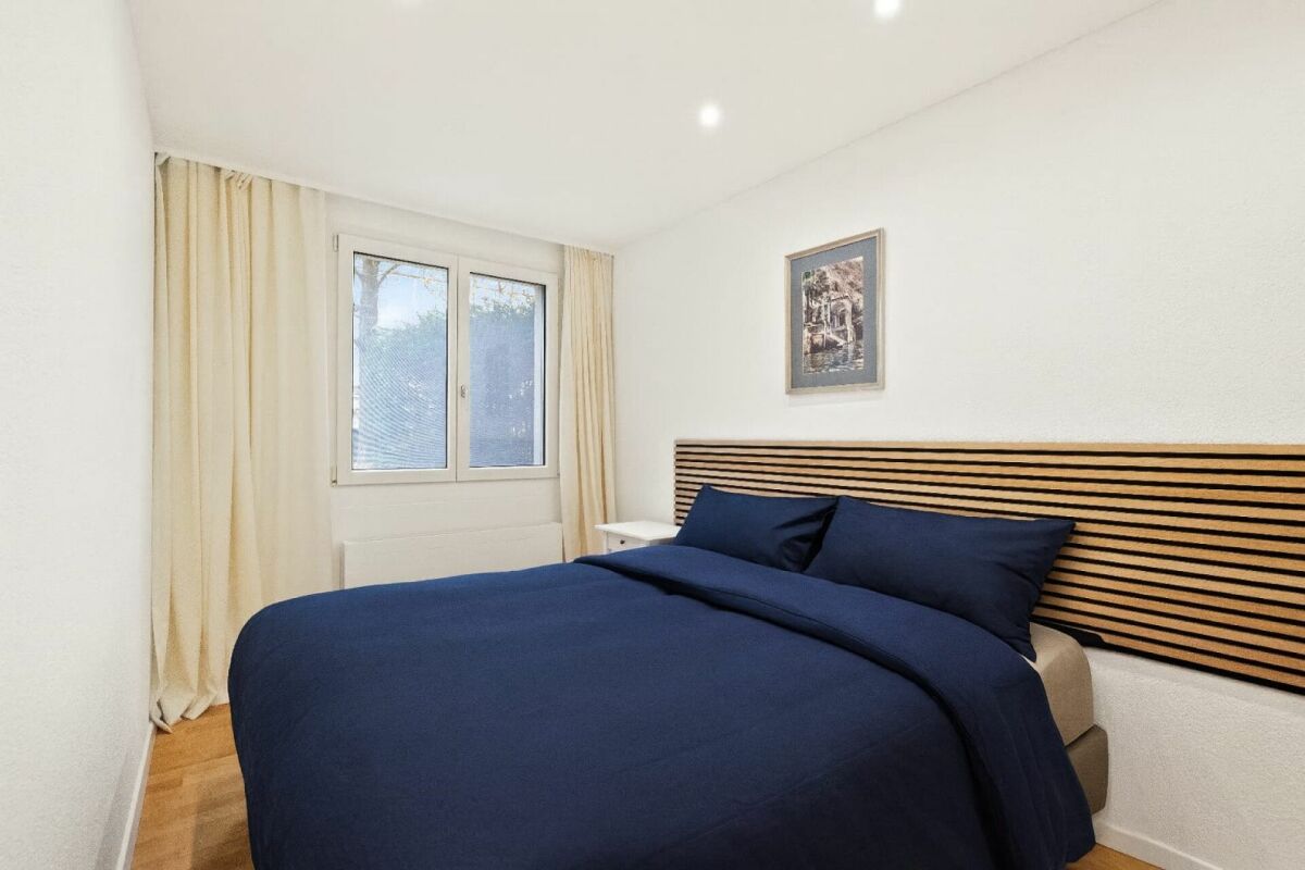 Schlafzimmer mit dunklem Bett und hellen Wänden