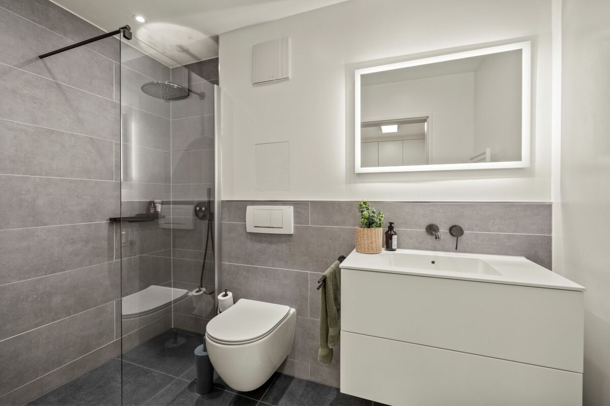 Modernes Badezimmer mit Walk-in-Dusche und beleuchtetem Spiegel