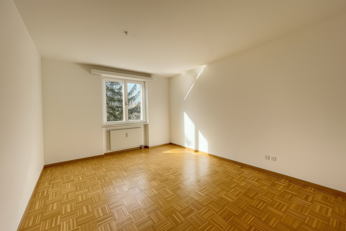 Leerer, heller Wohnraum mit Parkett und Fenster