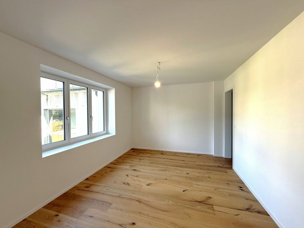 Helles, leeres Zimmer mit Holzboden und Fenster