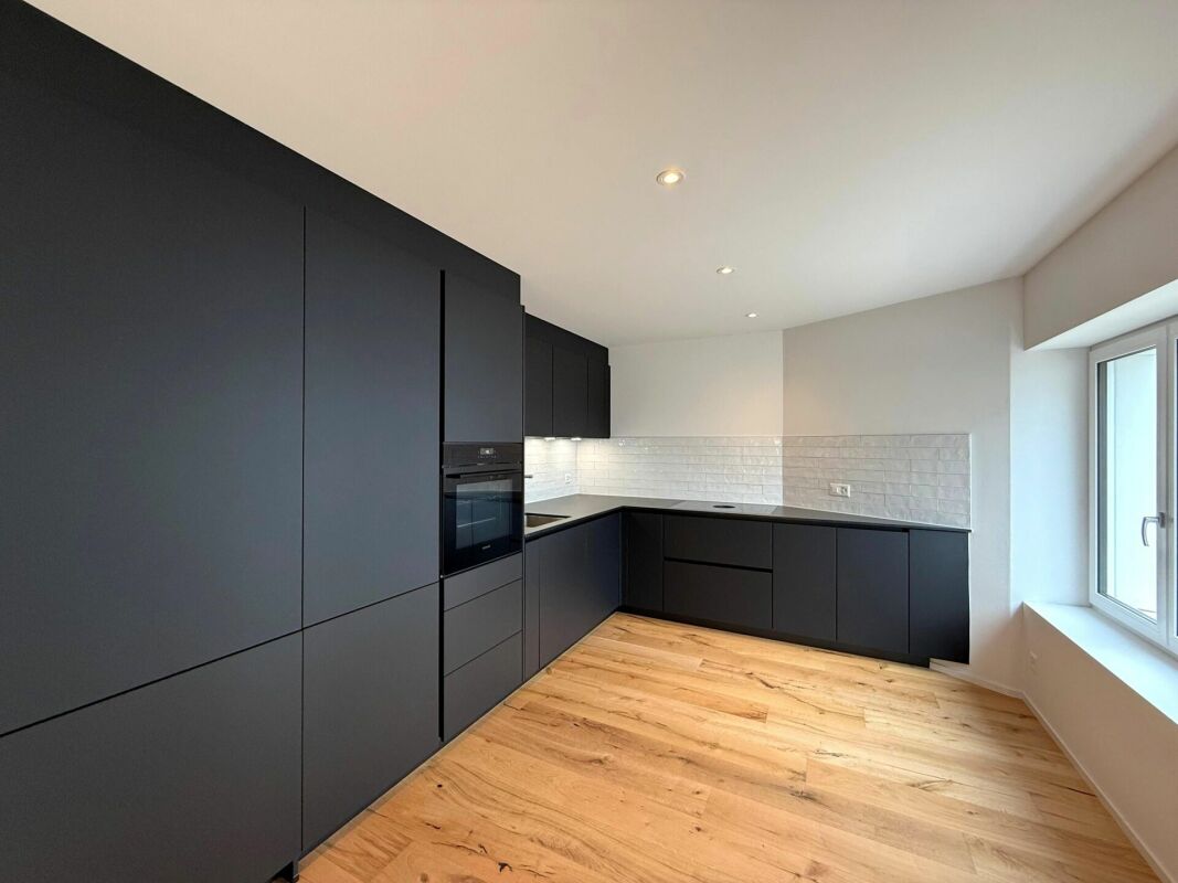 Moderne Küche mit dunklen Fronten und Holzfußboden