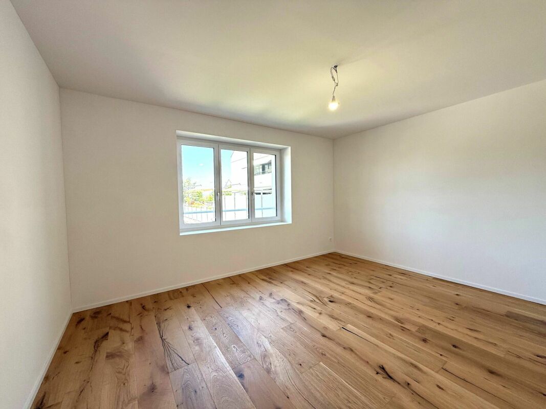 Leeres, frisch renoviertes Zimmer mit Parkett und Fenster