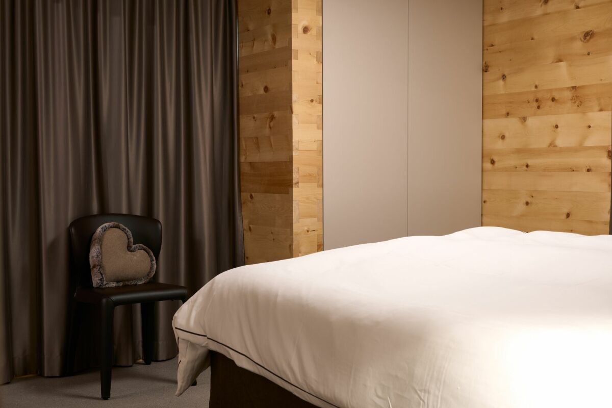 Gemütliches Schlafzimmer mit Holzverkleidung und dunklen Vorhängen