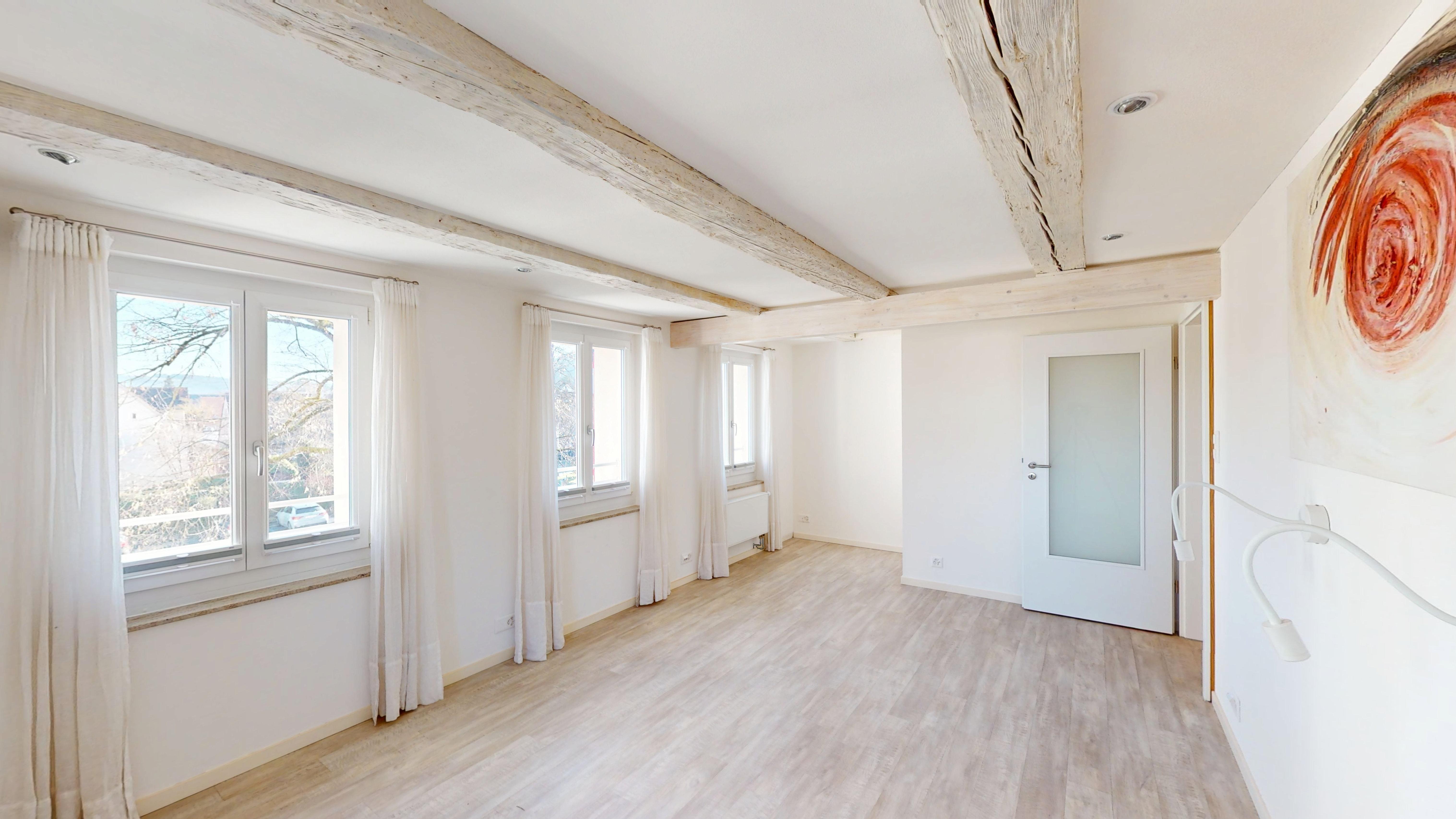 Heller leerer Raum mit Sichtbalken und Fenstern