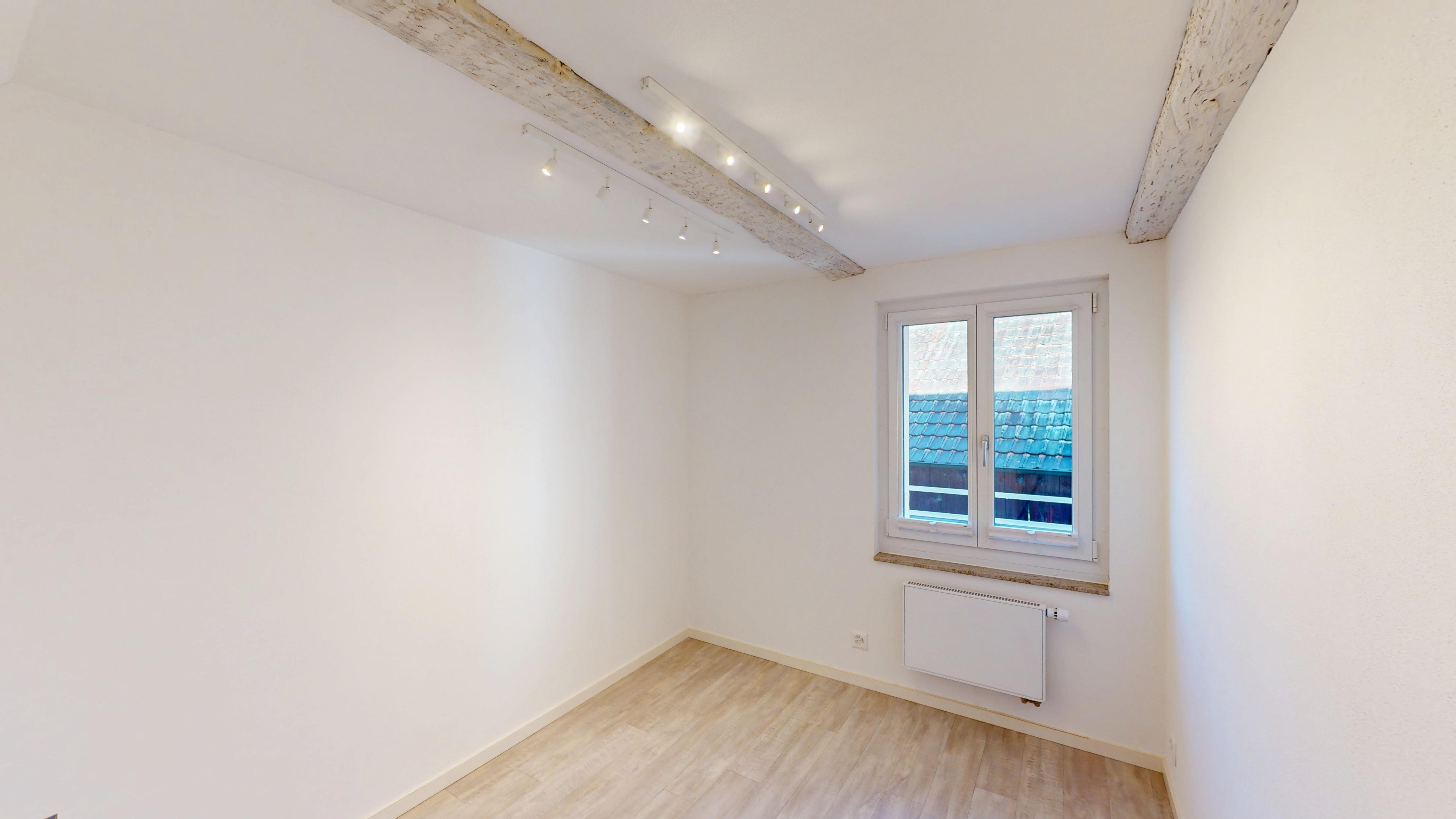 Heller leerer Raum mit Dachbalken und Fenster