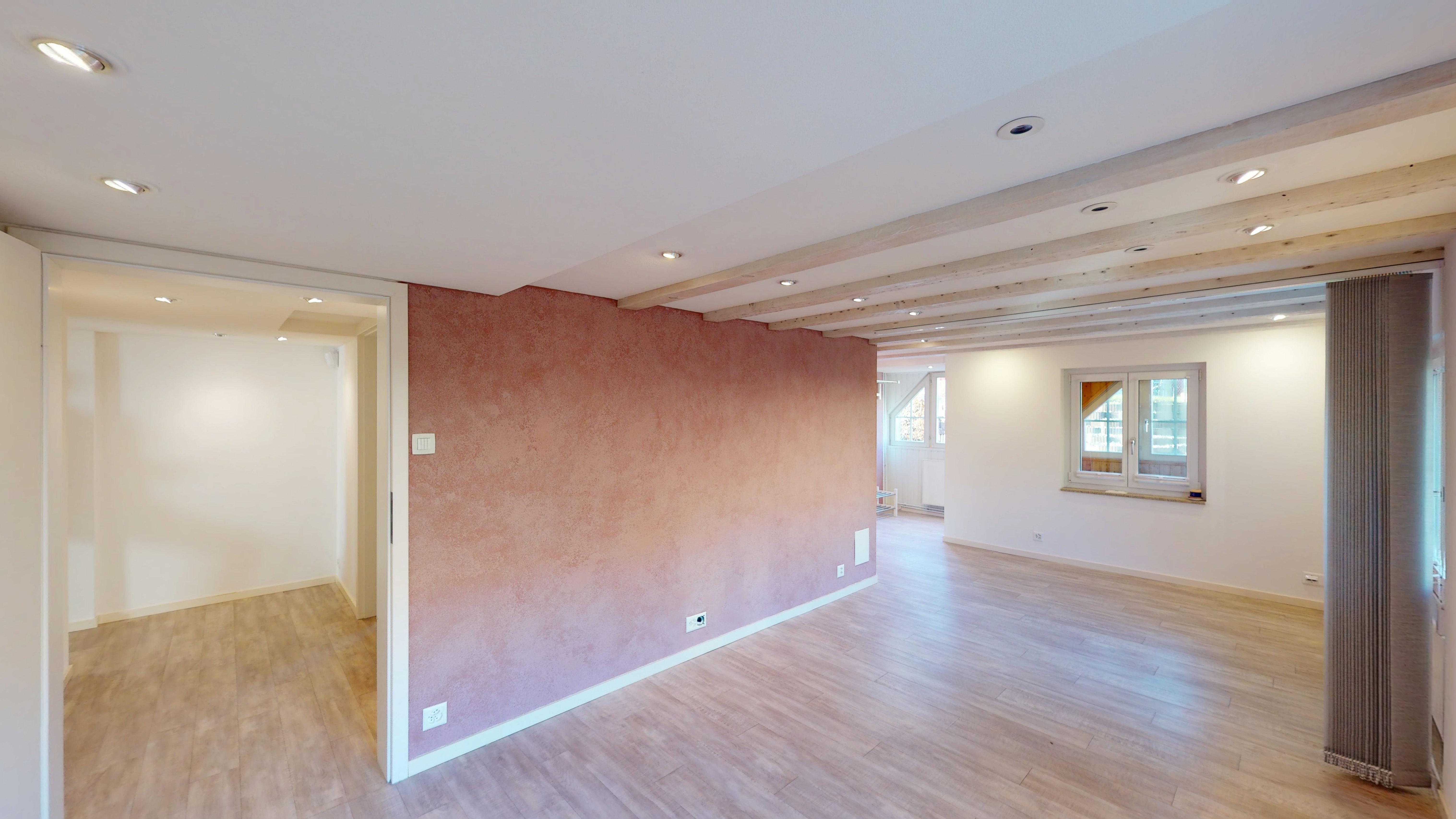 Helles, leeres Wohn- und Arbeitszimmer mit Holzdecke und großem Durchgang