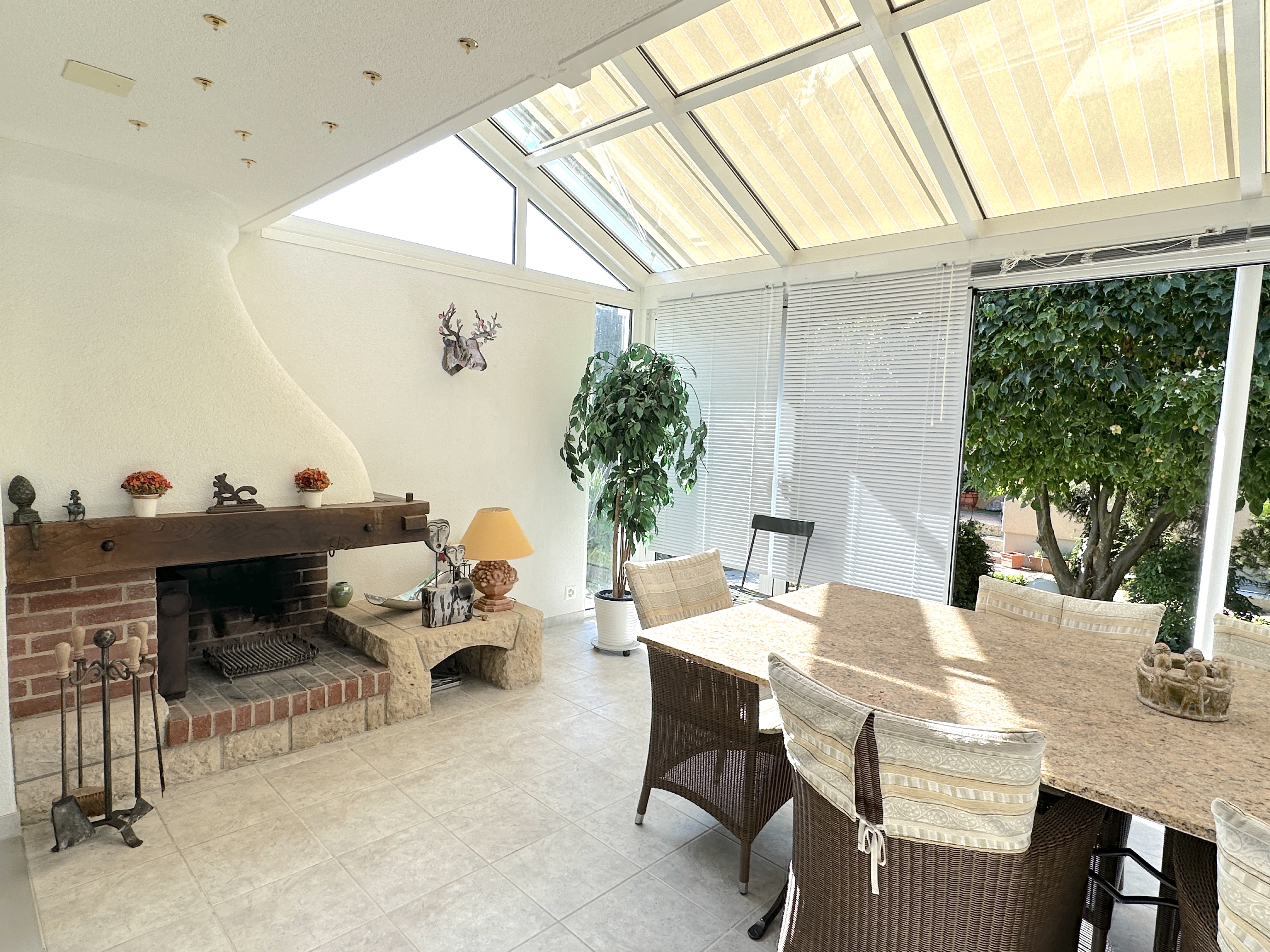 Verglaster Wintergarten mit Kamin und Esstisch