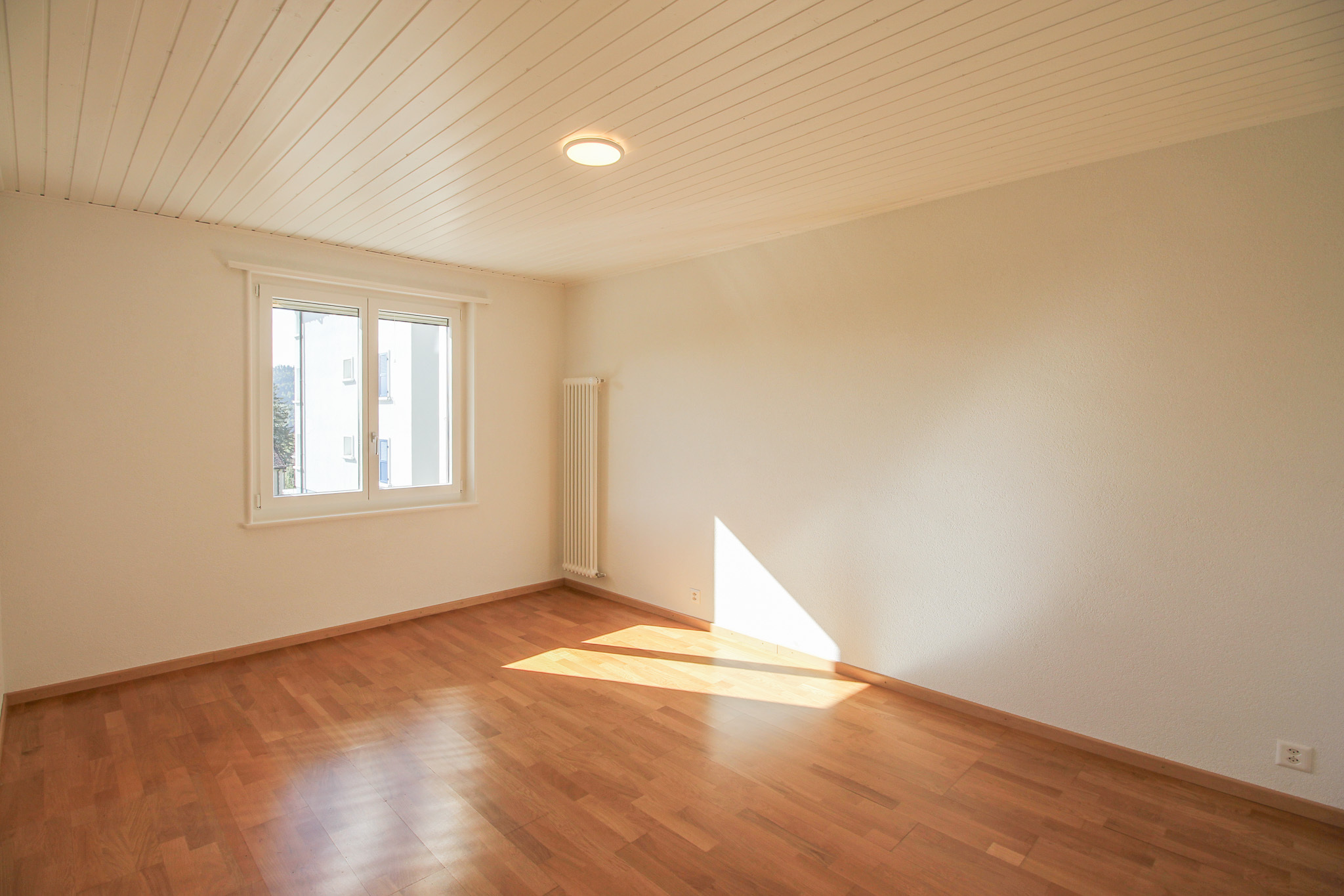 Helles, leeres Zimmer mit Holzfußboden