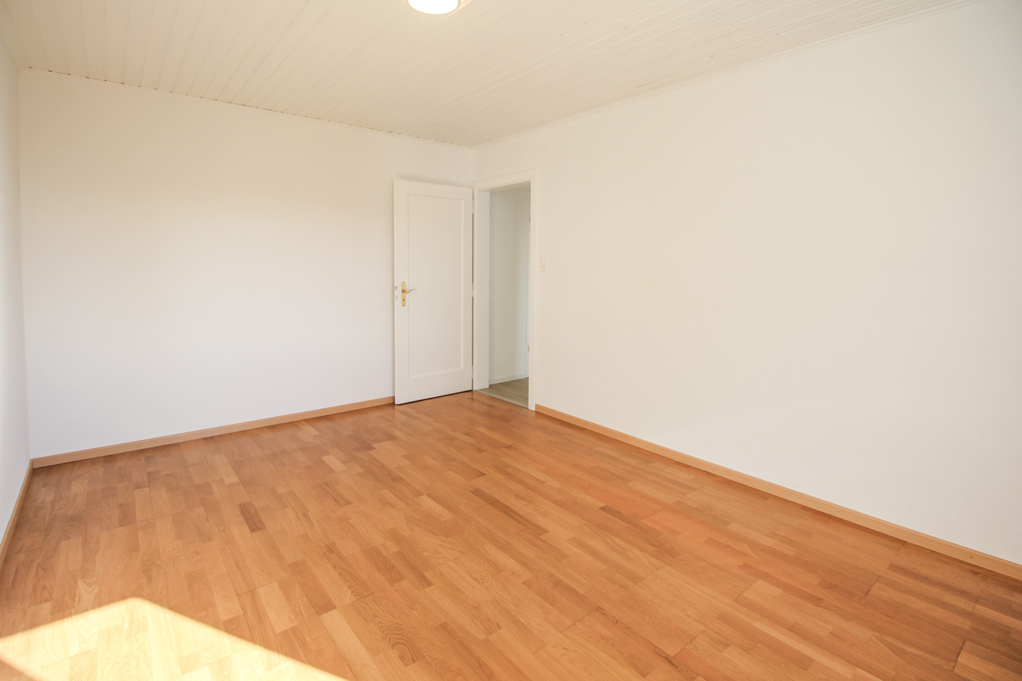 Leeres, helles Zimmer mit Holzboden