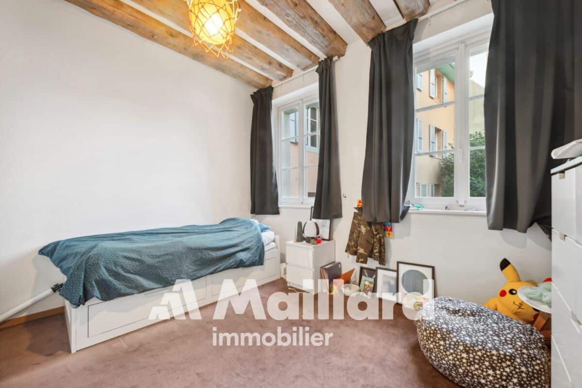 Gemütliches Schlafzimmer mit Sichtbalken und großen Fenstern