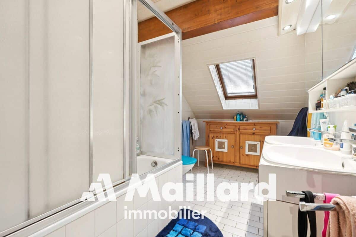 Dachgeschoss-Badezimmer mit Badewanne und Holzkommode
