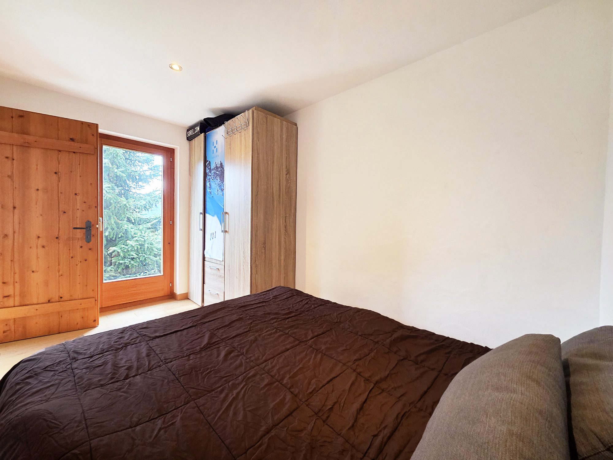 Helles Schlafzimmer mit Holztür und Naturblick