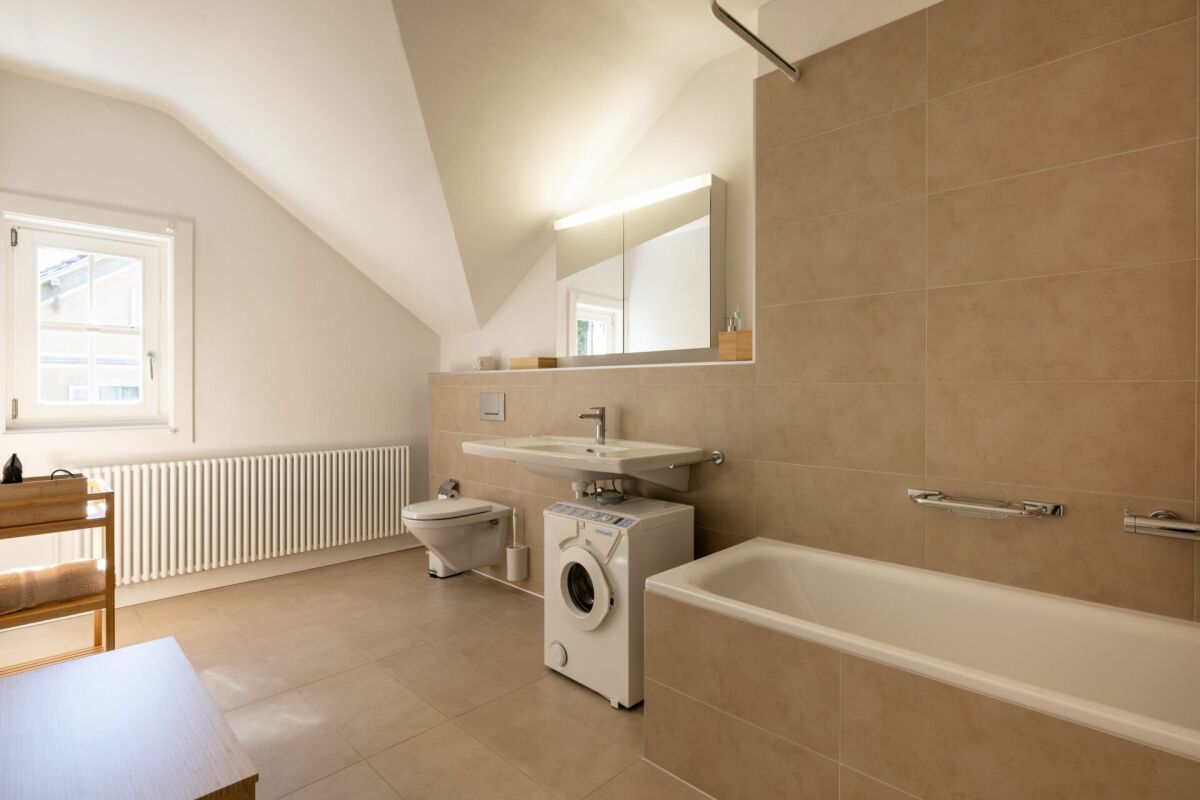 Helles Badezimmer mit Badewanne und Waschbecken unter Dachschräge