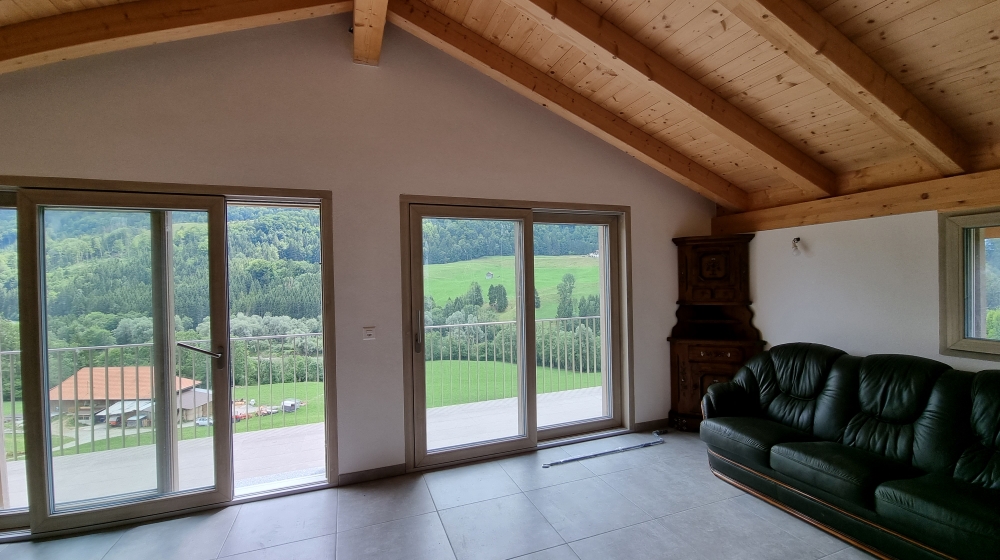 Wohnraum mit Panoramafenstern und Holzbalkendecke