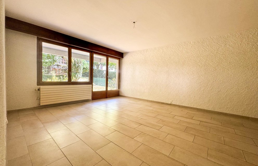 Leerer Wohnraum mit Terrassentür und großem Fenster