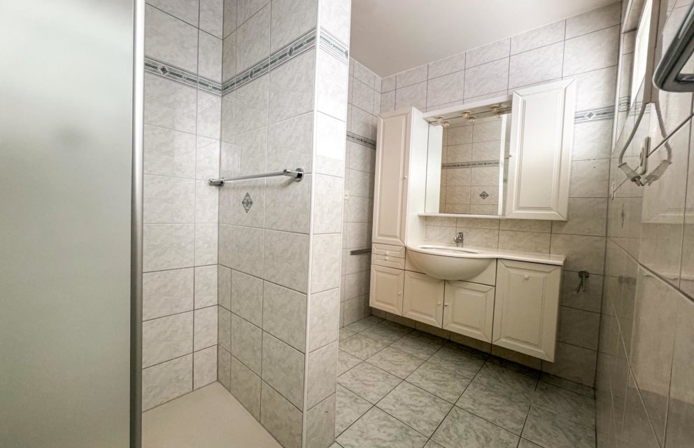 Helles Badezimmer mit gefliester Dusche und Waschplatz
