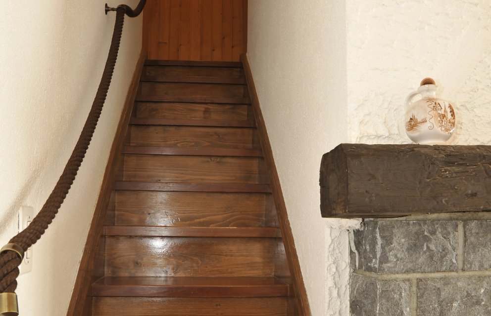 Holztreppe im Innenbereich mit rustikalem Kaminaufsatz