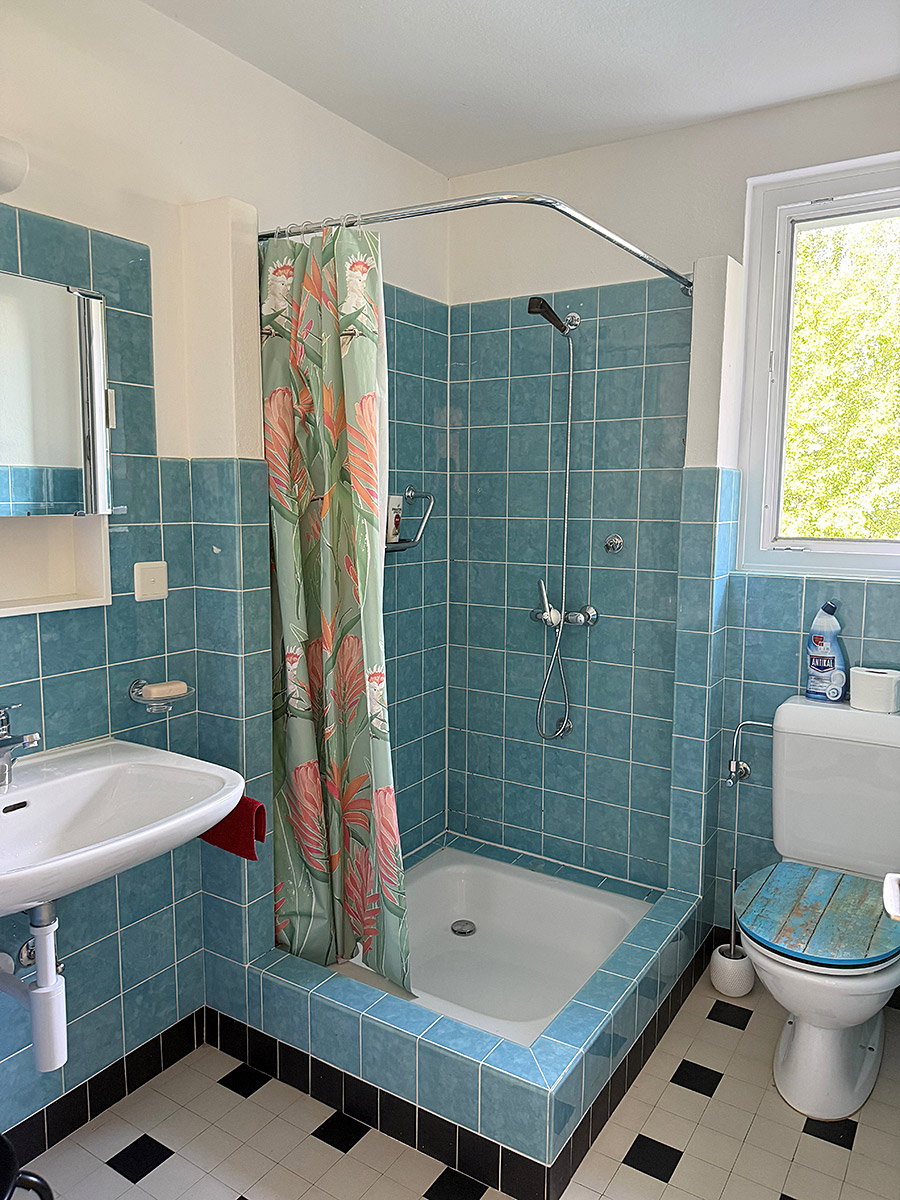 Badezimmer mit türkisfarbenen Fliesen und Duschbereich