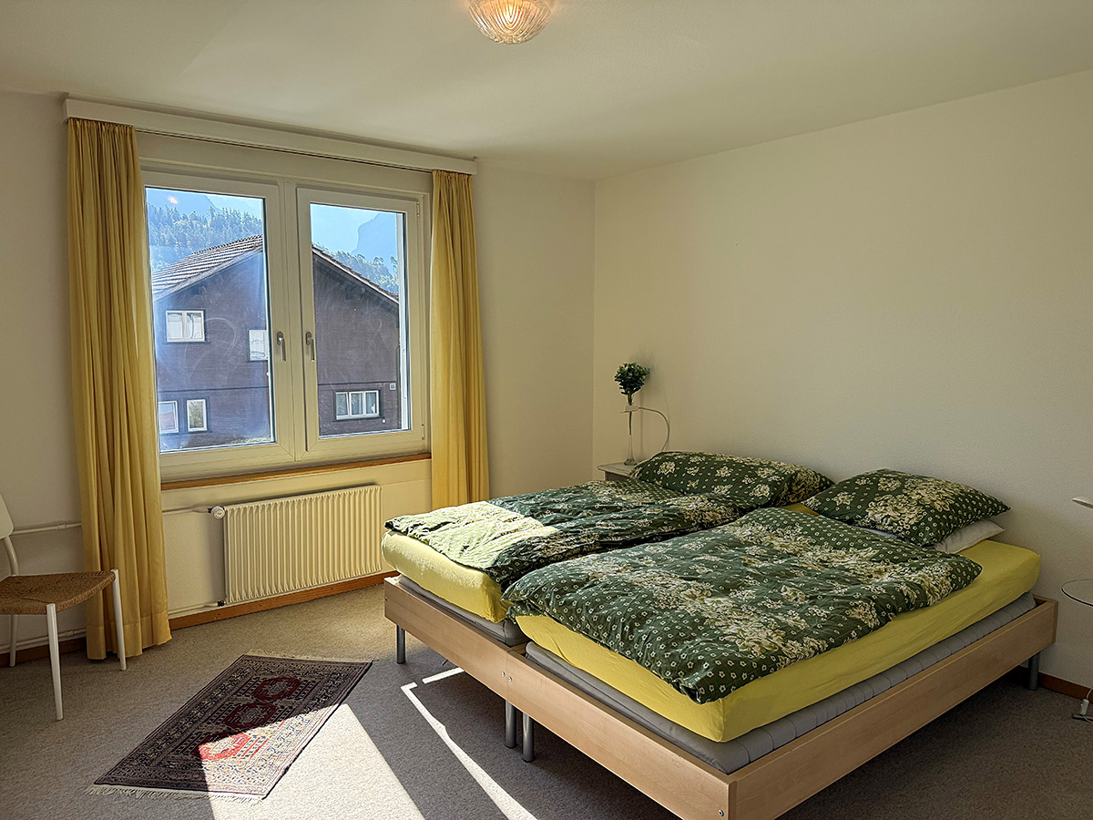 Helles Schlafzimmer mit Doppelbett und Fensterblick