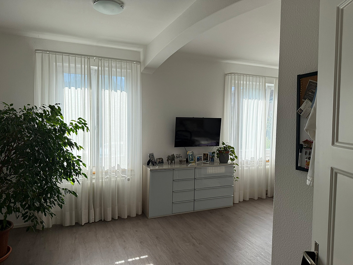 Heller Wohnraum mit zwei großen Fenstern und Sideboard