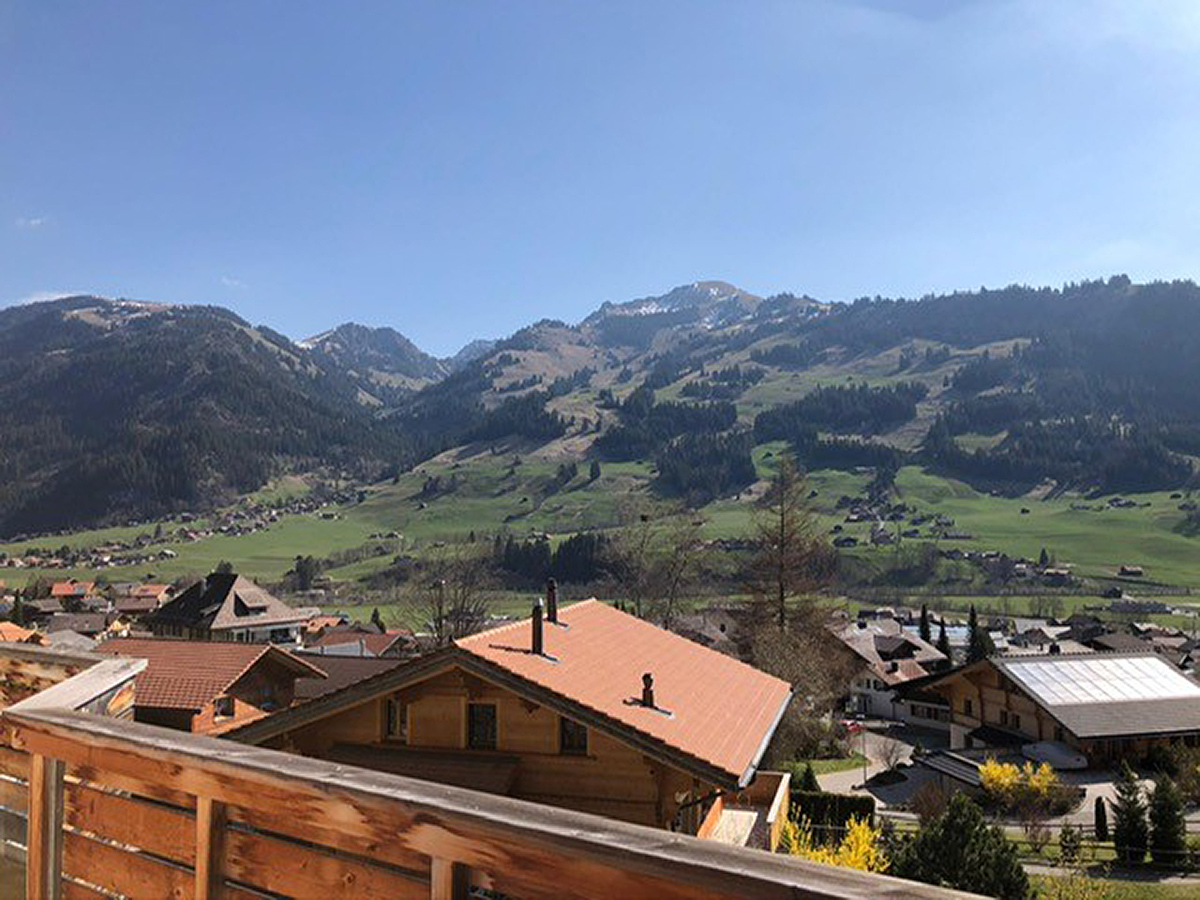 Alpenpanorama mit Dorf und Holzbalkon