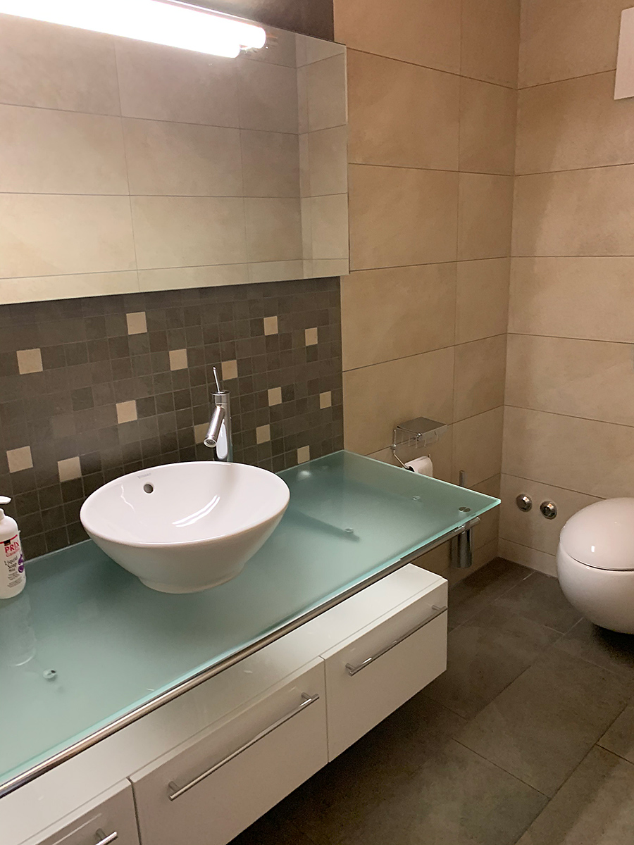 Modernes Badezimmer mit Glaswaschtisch und Aufsatzbecken