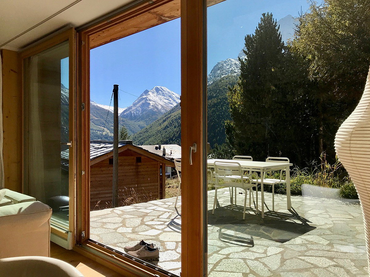 Blick aus einem Wohnraum auf Terrasse und Berglandschaft