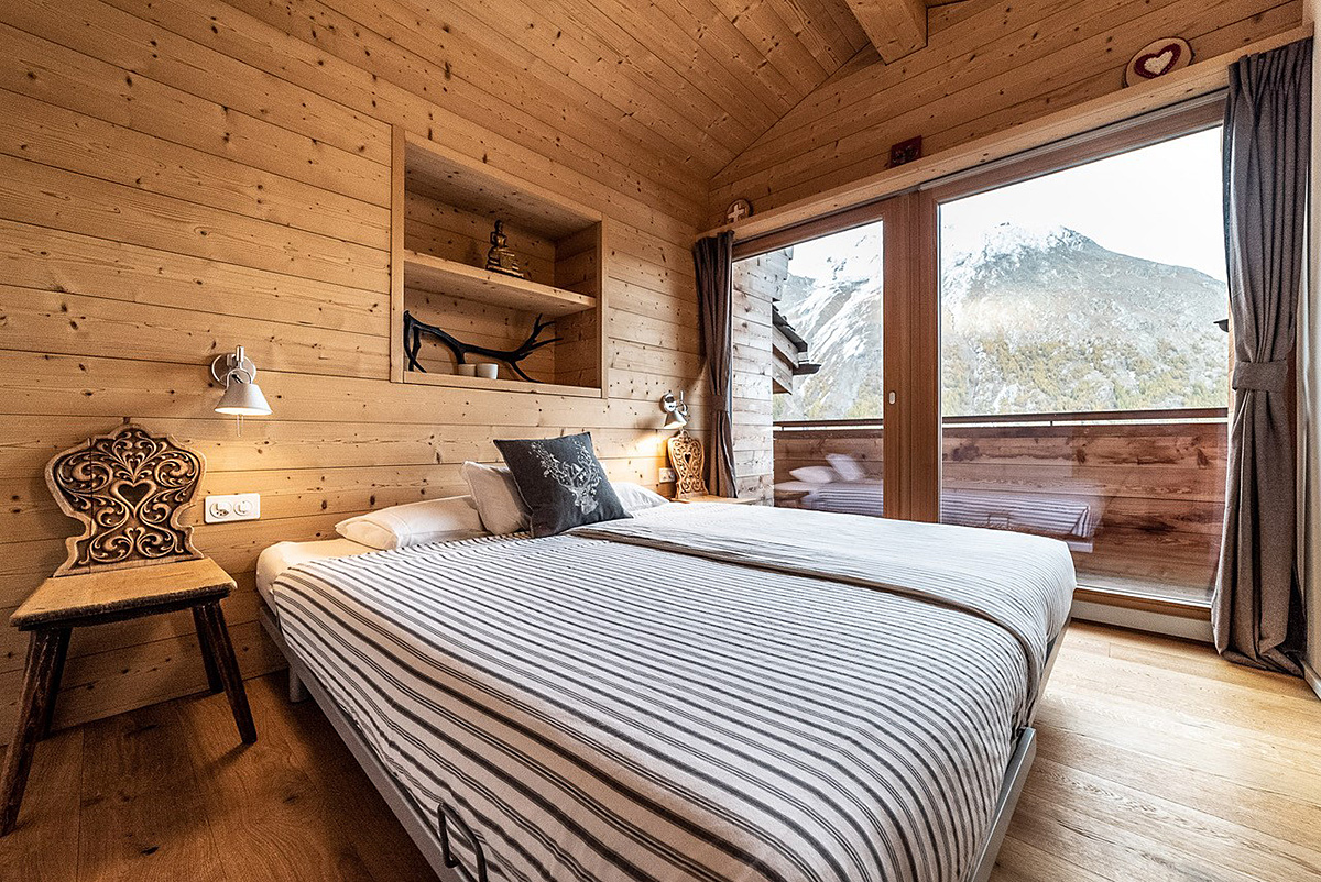 Gemütliches Holzzimmer mit Doppelbett und Bergblick