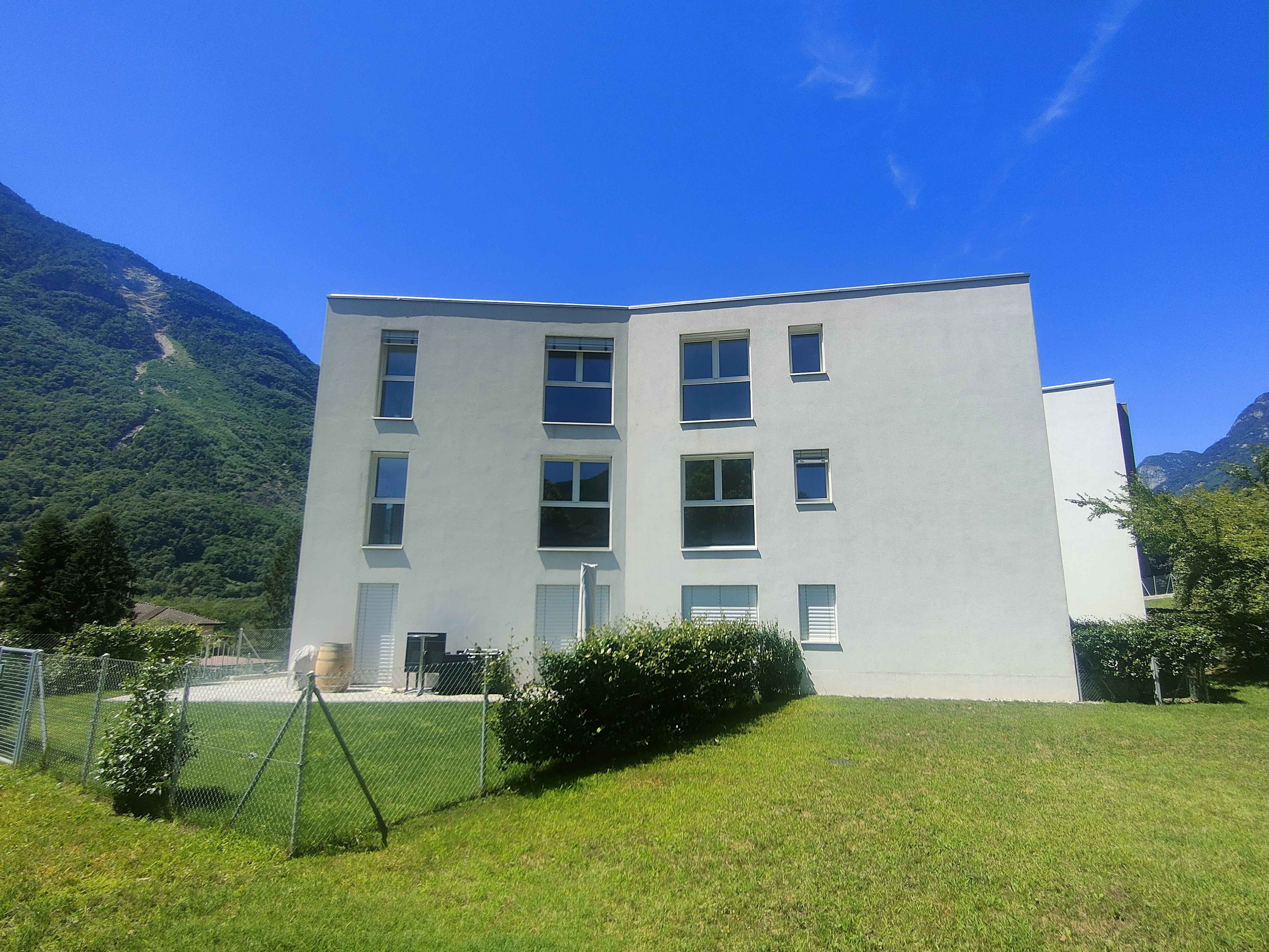 Modernes Wohngebäude mit Garten und Bergkulisse