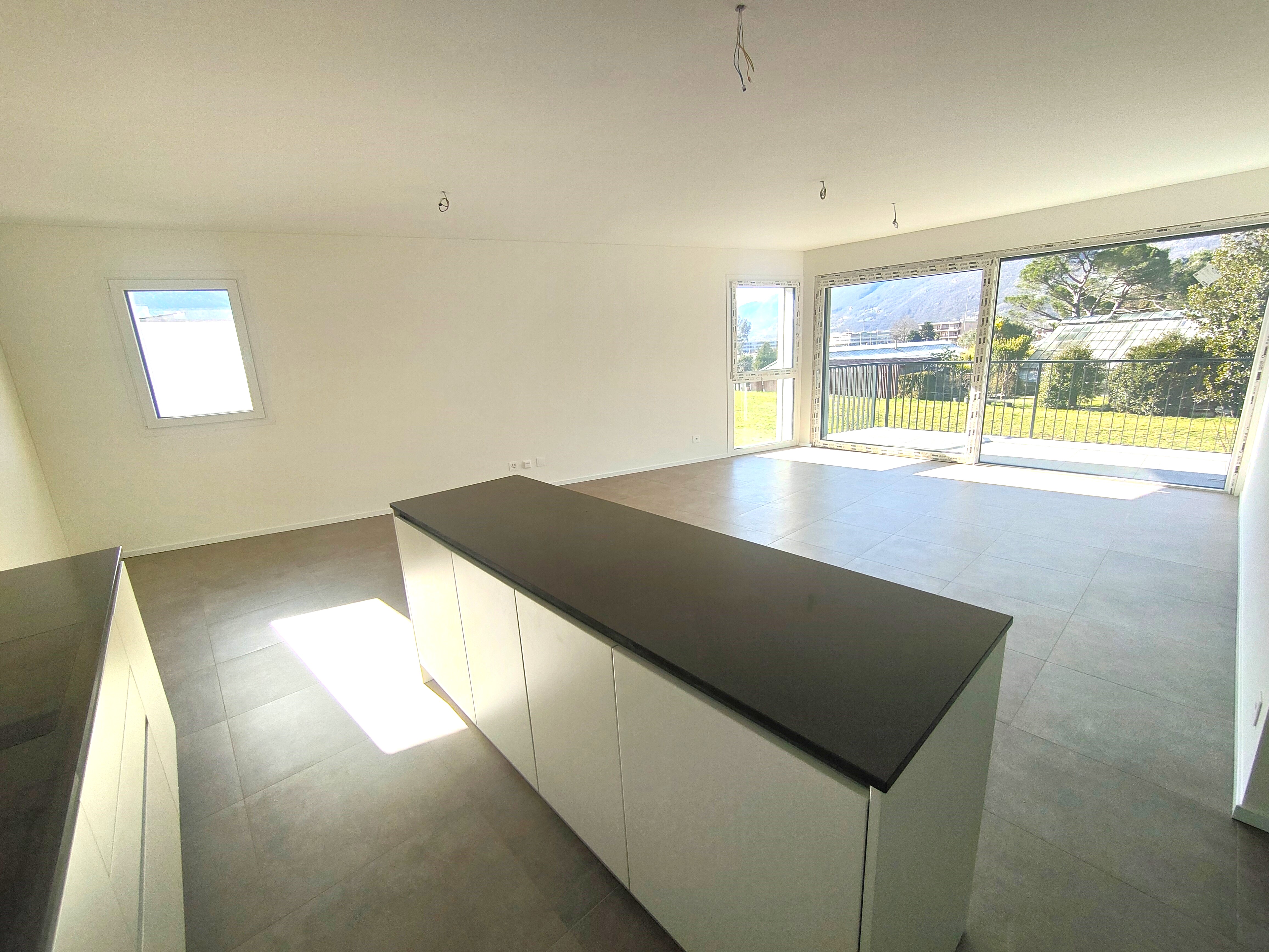 Helles, unfertiges Wohn-/Küchenzimmer mit Terrasse und Blick ins Grüne