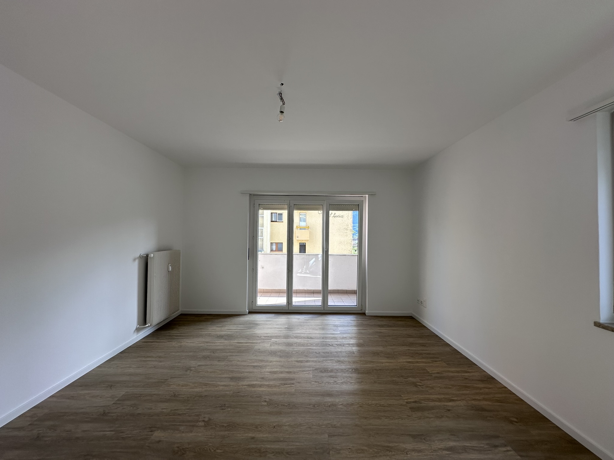 Leerer Wohnraum mit Balkonzugang