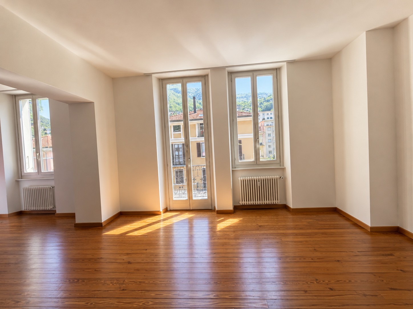 Heller leerer Wohnraum mit Holzboden und Fensterblick